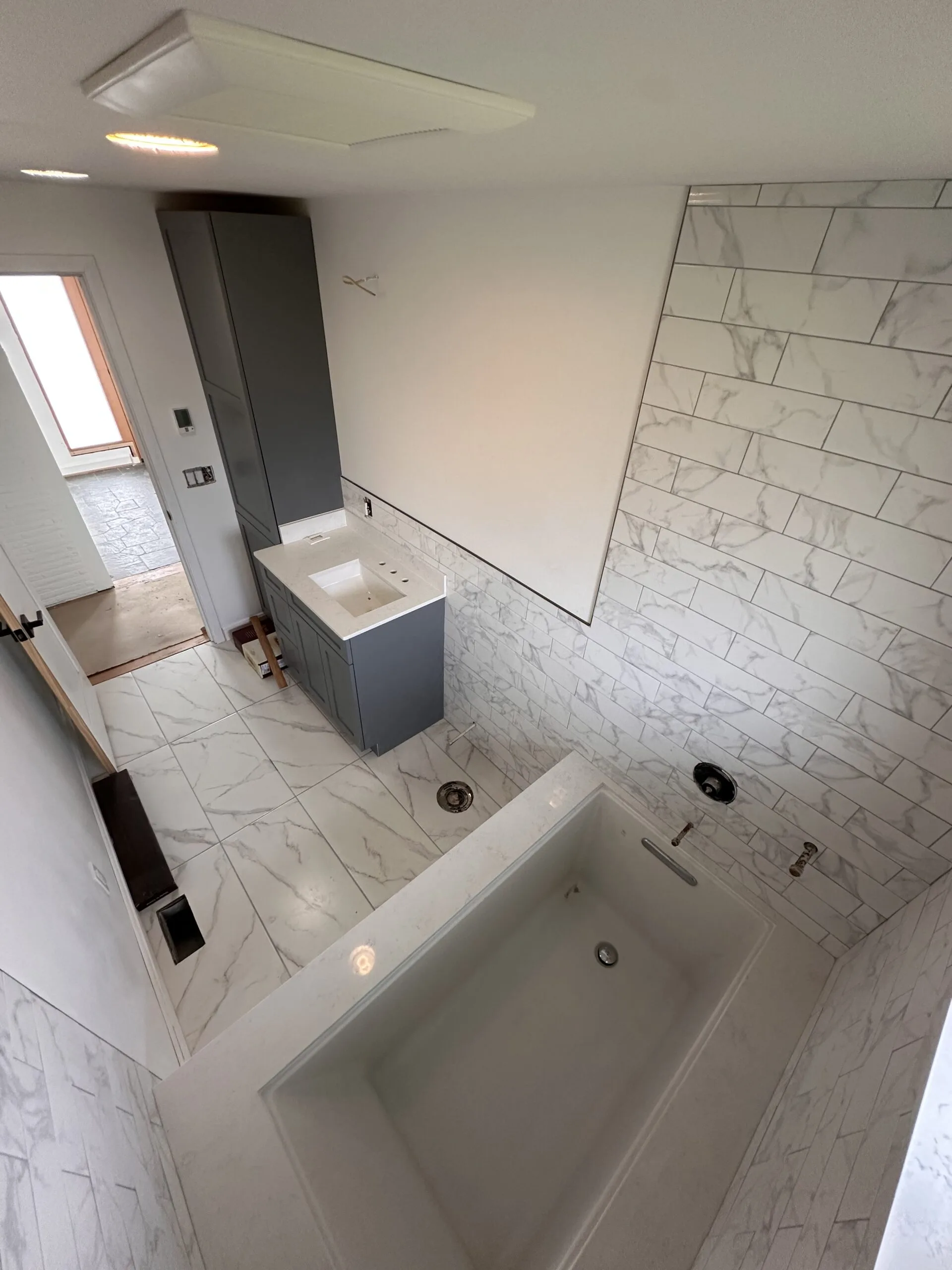 Master bathroom — Calacatta marble tile, soaking tub, gray vanity